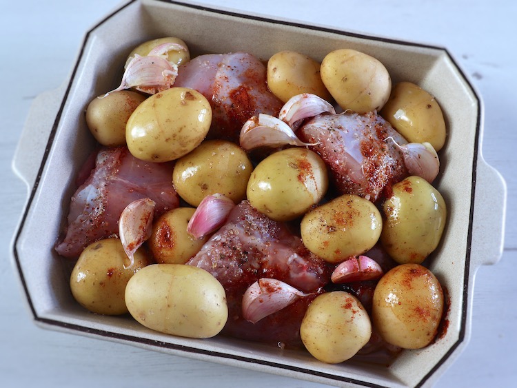 Coelho com batatas temperado com sal, alhos, pimenta, pimentão doce e azeite numa assadeira