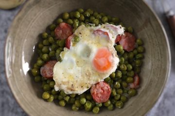 Ervilhas com ovos escalfados e chouriço num prato fundo