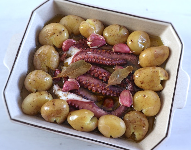 Octopus, potatoes, garlic, pepper, bay leaf and olive oil on a baking dish