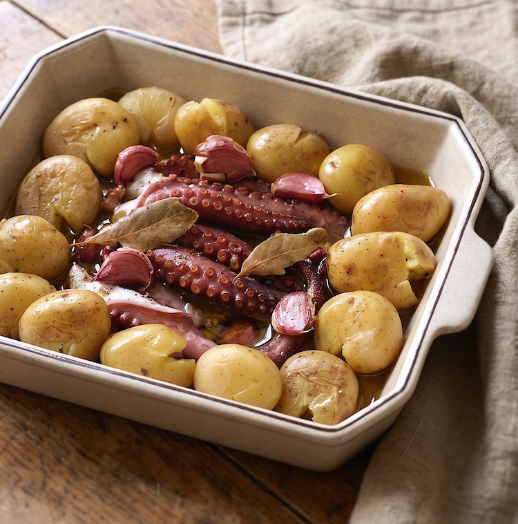Octopus with potatoes, garlic, olive oil, pepper, bay leaf and salt in a baking dish