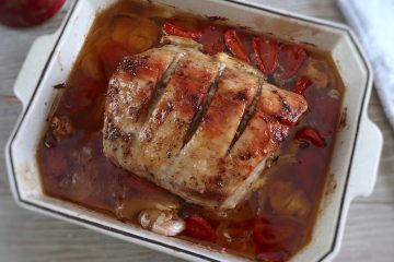 Roasted pork loin with tomato and onion on a baking dish