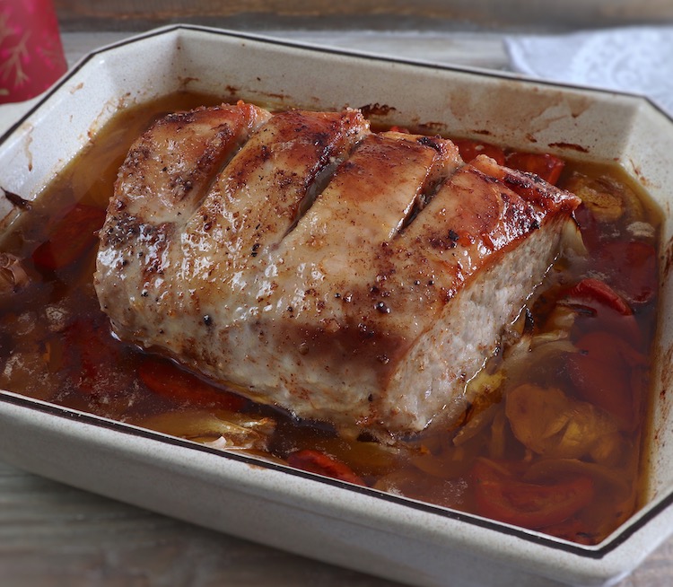 Pork loin in the oven with tomato and onion on a baking dish