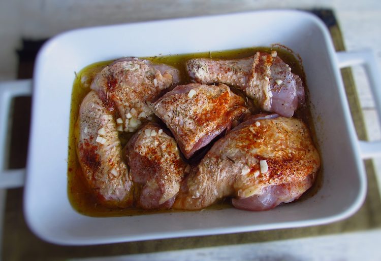 Chicken on a baking dish seasoned with salt, lemon juice, pepper, nutmeg, chopped garlic, paprika and thyme