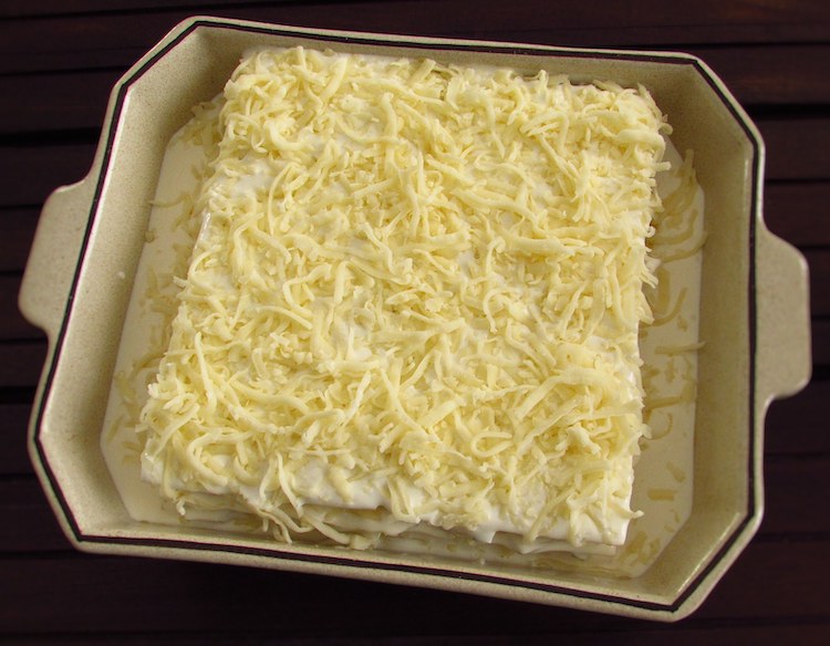Lasagna sheets, cod, egg béchamel and grated cheese on a baking dish