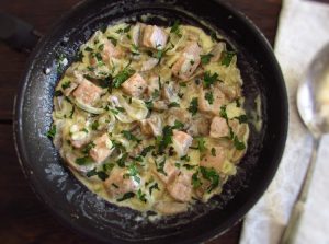Salmon with cream and mushrooms on a frying pan