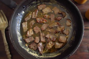 Steaks with mustard sauce on a frying pan