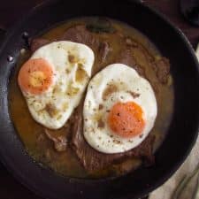 Veal steak with egg on a frying pan