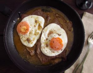Veal steak with egg on a frying pan