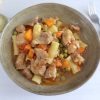 Pork stew with peas, carrot and pasta on a dish bowl