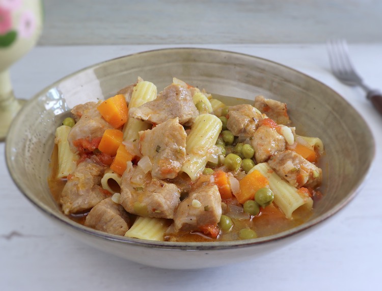 Pork stew with peas, carrot and pasta on a dish bowl