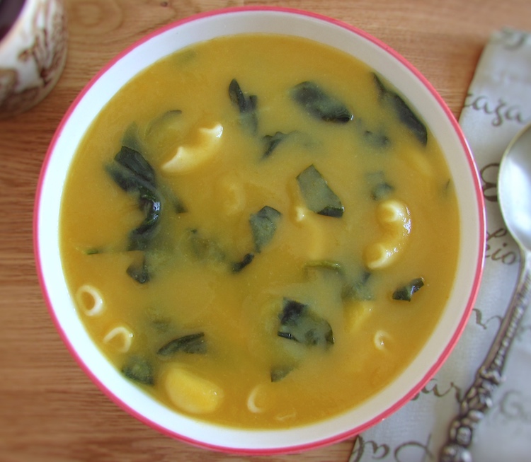 Spinach soup with elbow pasta on a soup bowl