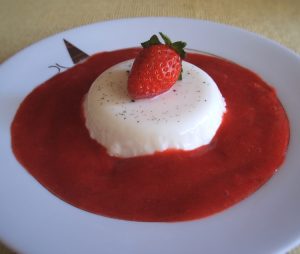 White chocolate panna cotta with strawberry sauce on a plate