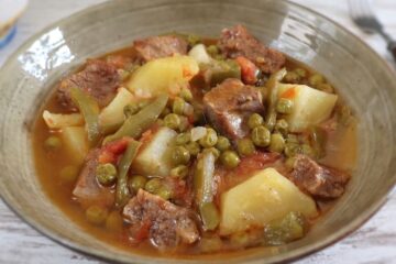 Carne estufada com batatas e ervilhas num prato fundo