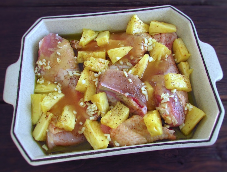 Chicken with pineapple seasoned with salt, pepper, nutmeg, chopped garlic, honey and olive oil on a baking dish