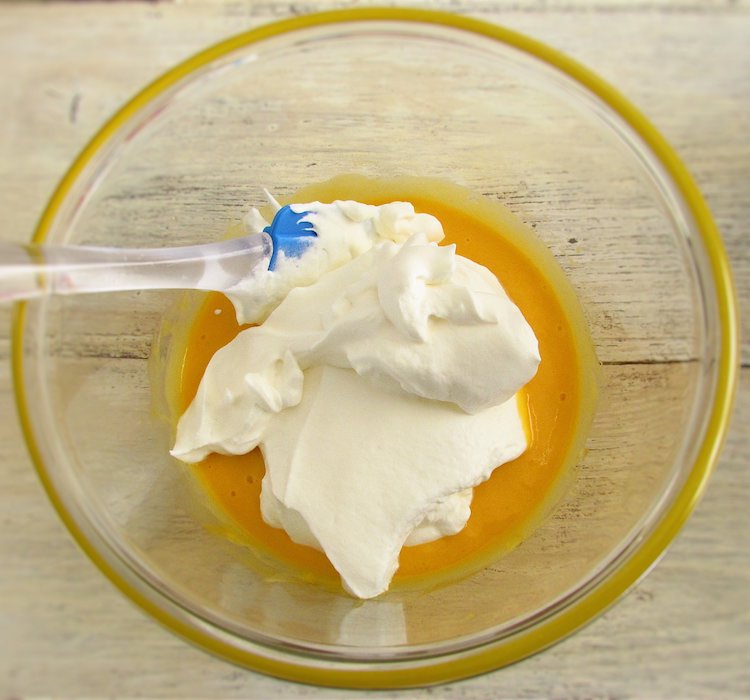 Mango pulp, yogurt and gelatin sheets mixture with whipped cream on a glass bowl