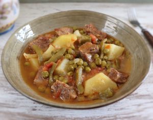 Beef stew with potatoes and peas on a dish bowl