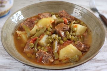 Beef stew with potatoes and peas on a dish bowl