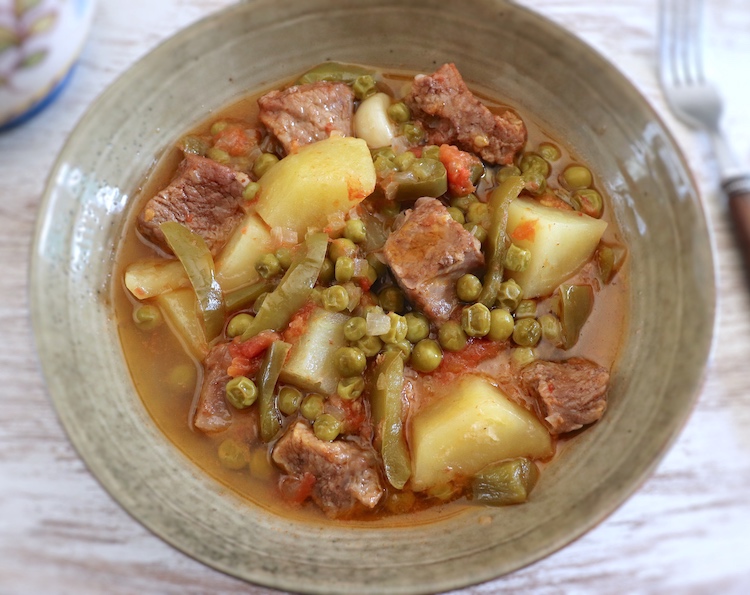 Stewed meat with potatoes and peas on a dish bowl