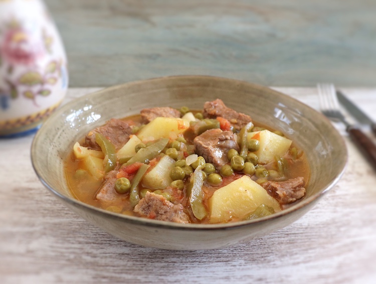 Stewed meat with potatoes and peas on a dish bowl