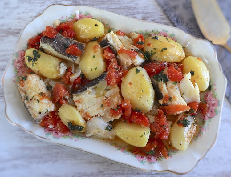 Baked cod with onion and tomato on a platter