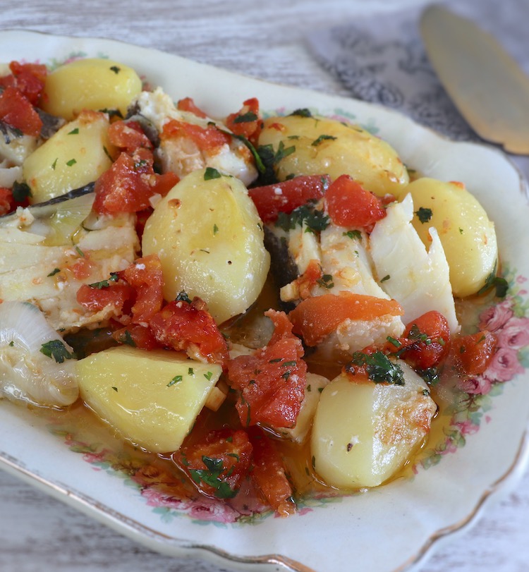 Cod with onion and tomato in the oven on a platter