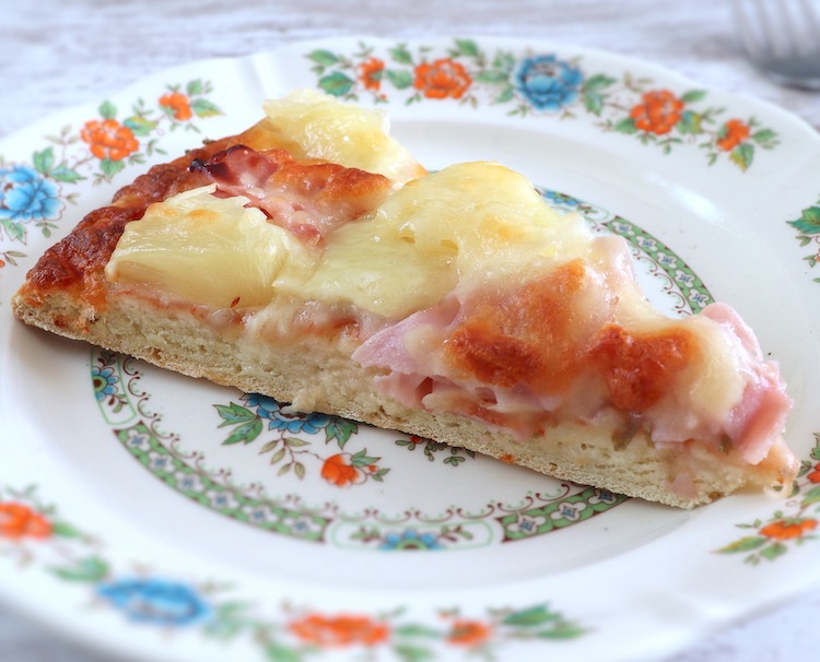 Slice of ham and pineapple pizza on a plate