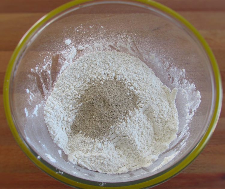 Mixed flour and salt in a glass bowl with baker's yeast