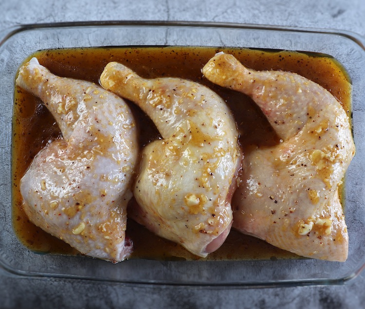 Chicken legs seasoned with honey sauce on a glass baking dish