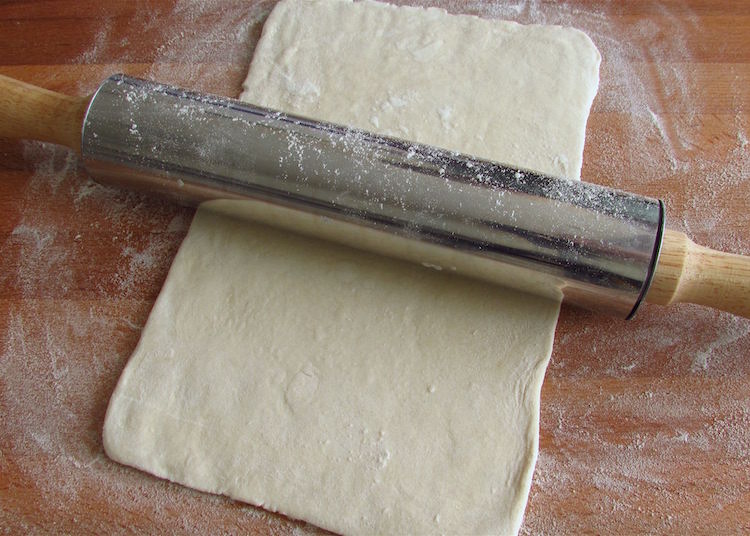 Puff pastry on a wooden table sprinkled with flour