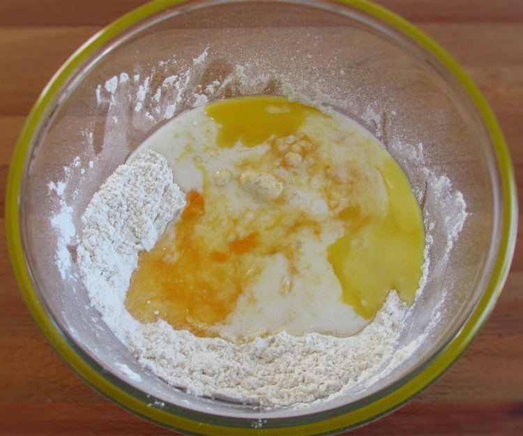 Flour mixture with milk, beaten egg, sugar and melted margarine on a bowl