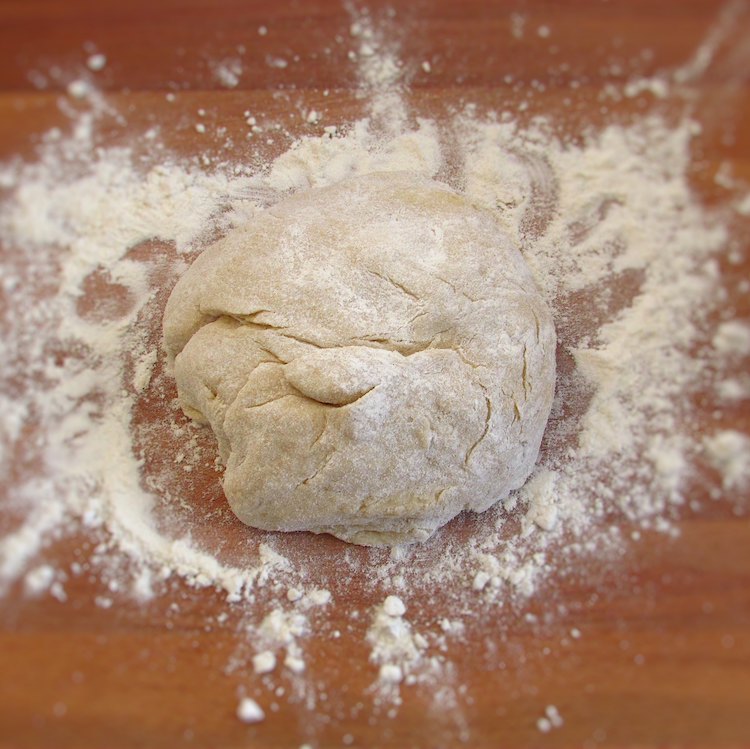 Milk bread dough on a wooden board sprinkled with flour
