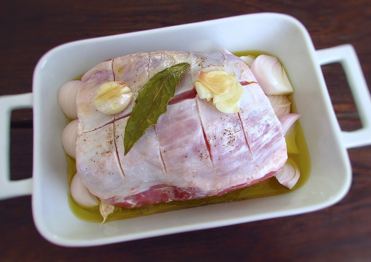 Pork loin on a baking dish seasoned with salt, 6 unpeeled crushed garlic, white wine, onions cut into quarters, bay leaf, pepper and 100 ml (1/2 cup) olive oil