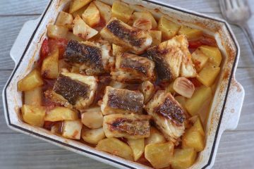 Baked cod with tomato and potatoes on a baking dish