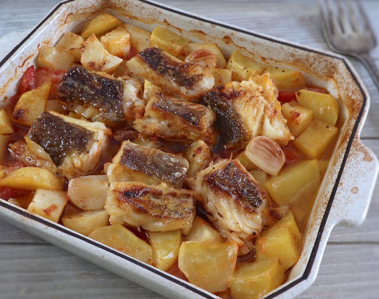 Cod in the oven with tomato and potatoes on a baking dish