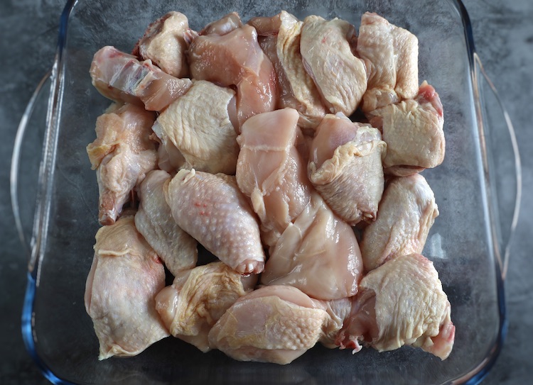 Chicken cut into pieces on a glass baking dish