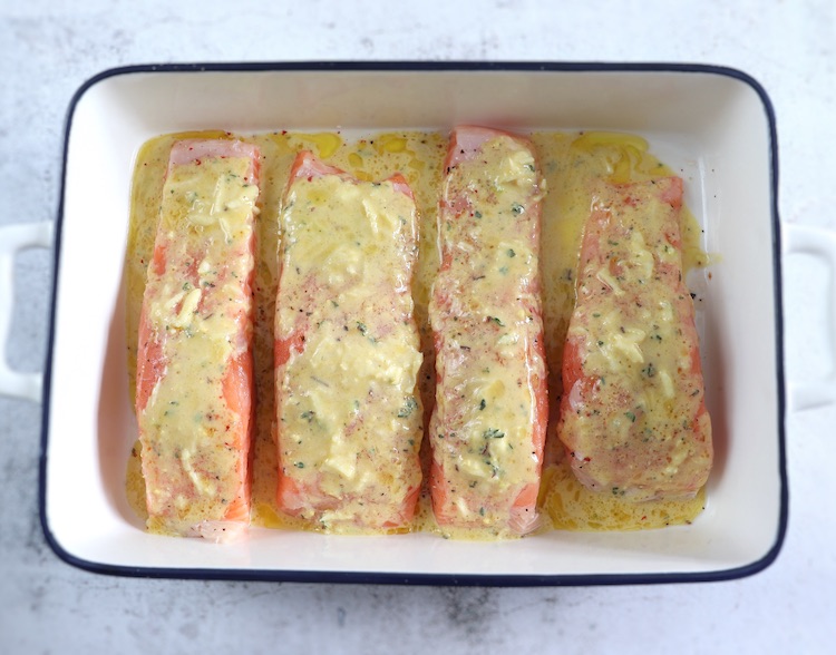 Salmon fillets season with lemon and mustard sauce on a baking dish