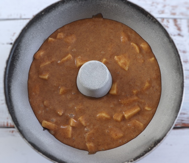 Massa de bolo de maçã e canela numa forma de bolos redonda com furo no meio