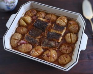 Baked cod with potatoes, olive oil and lemon on a baking dish