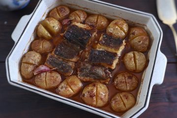 Baked cod with potatoes, olive oil and lemon on a baking dish