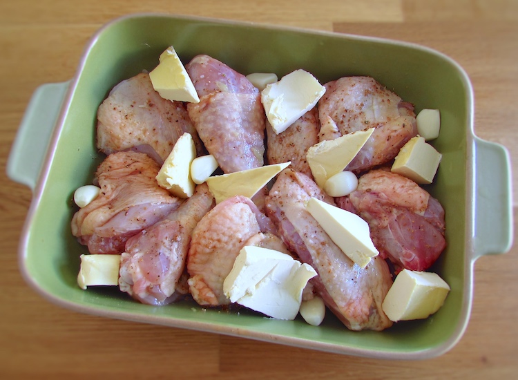 Chicken seasoned with salt, lemon juice, Worcestershire sauce, pepper, peeled garlic, nutmeg and margarine on a baking dish