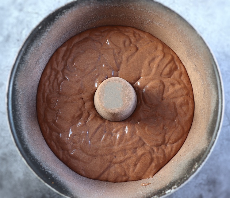 Massa de bolo doce de chocolate numa forma de bolos redonda com furo no meio