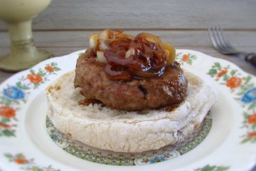 Burger with caramelized onion with a bread slice on a plate