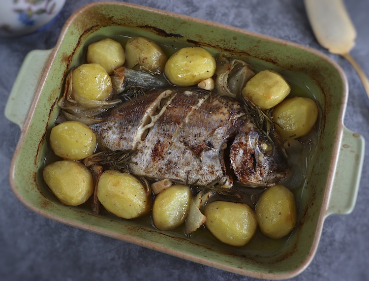 Baked sea bream with potatoes on a baking dish