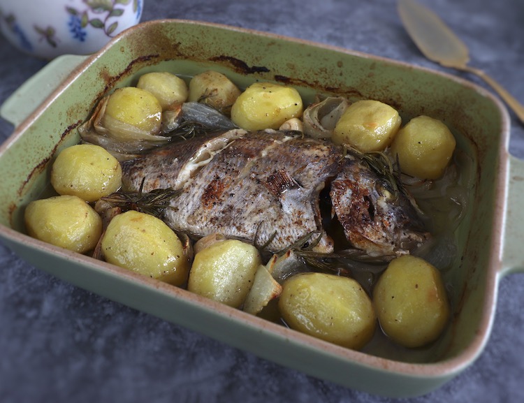 Baked sea bream with potatoes on a baking dish