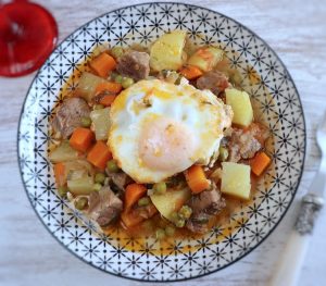 Beef stew with potatoes and poached eggs on a plate