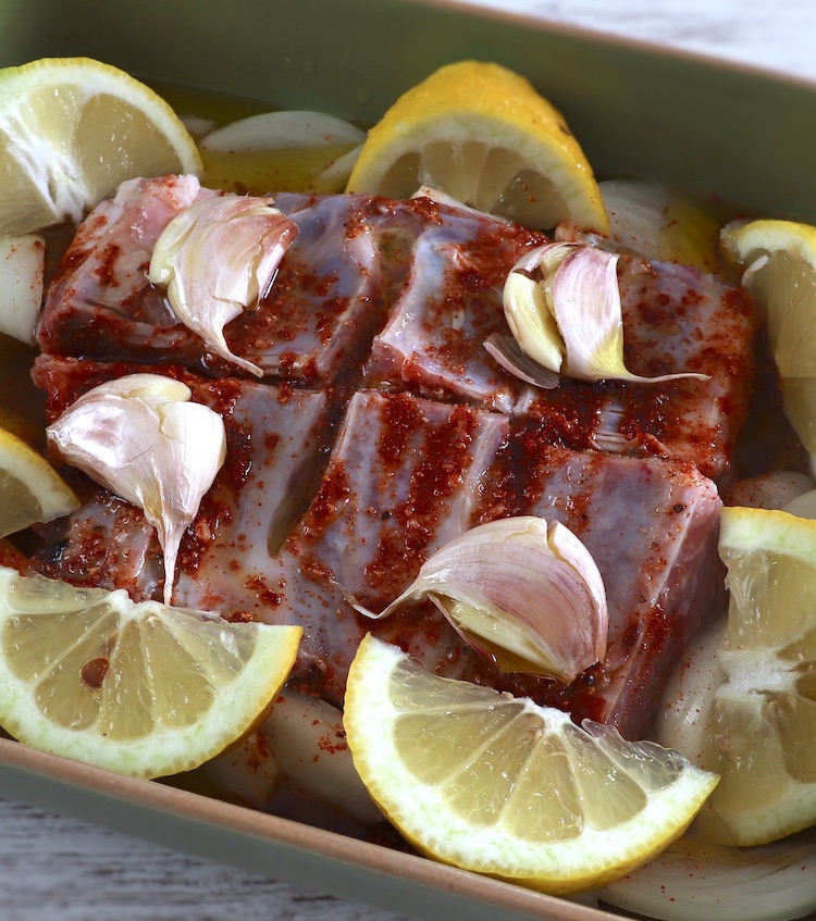 Pork ribs seasoned with spices, garlic, olive oil and lemon on a baking dish