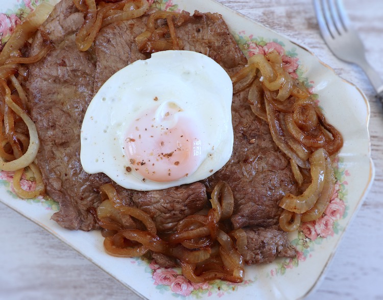 Fried beef steaks with fried egg on a platter