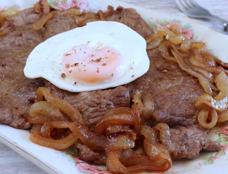 Fried beef steaks with fried egg on a platter