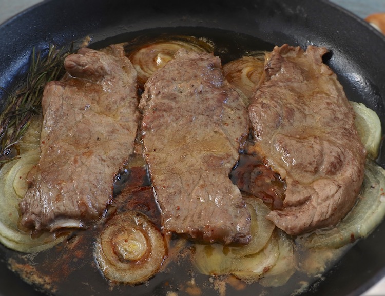 Fried beef steaks on a frying pan