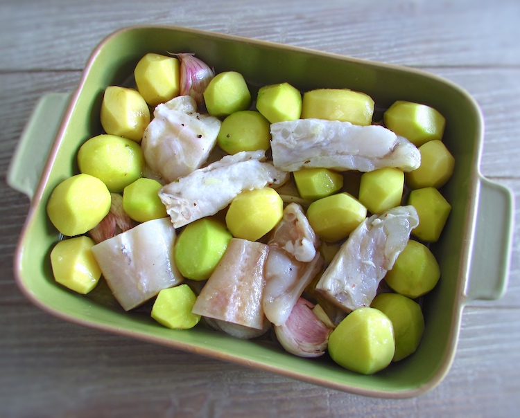 Monkfish and potatoes on a baking dish seasoned with lemon juice, white wine, pepper and salt